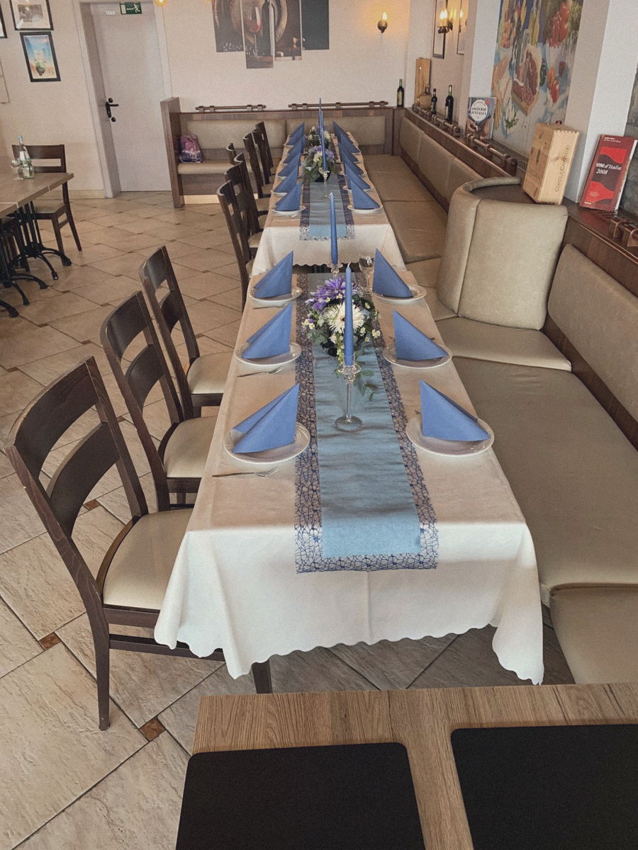 Lange eingedeckte Tafel mit blauen Servietten und Blumen